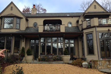 Large elegant beige two-story wood house exterior photo in Other with a hip roof and a shingle roof