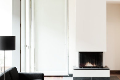 Mittelgroßes Modernes Wohnzimmer im Loft-Stil mit weißer Wandfarbe, dunklem Holzboden, Kaminofen und verputzter Kaminumrandung in Berlin