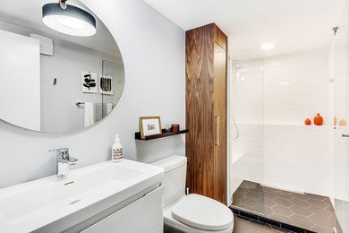 Design ideas for a mid-sized contemporary 3/4 bathroom in Chicago with furniture-like cabinets, white cabinets, an alcove shower, a one-piece toilet, white tile, ceramic tile, grey walls, porcelain floors, an integrated sink, grey floor, a sliding shower screen and white benchtops.