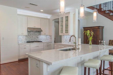 Example of a large transitional u-shaped medium tone wood floor and brown floor kitchen design in Los Angeles with an undermount sink, recessed-panel cabinets, white cabinets, quartz countertops, white backsplash, marble backsplash, stainless steel appliances and white countertops