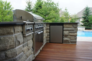 Inspiration for a large timeless backyard stone patio kitchen remodel in Orange County
