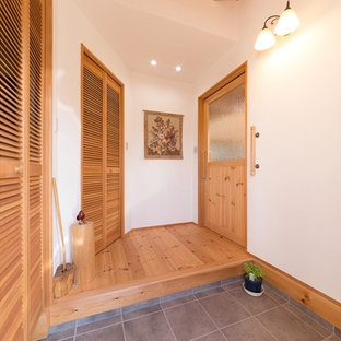 他の地域の引き戸アジアンスタイルのおしゃれな玄関 (白い壁、グレーの床、黒いドア) の写真