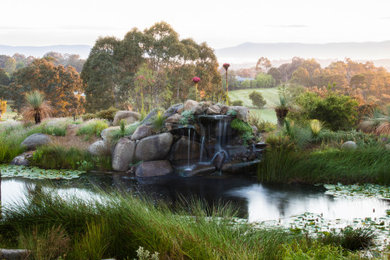 Design ideas for a large sloped full sun formal garden for spring in Melbourne with with pond and gravel.