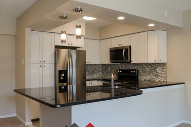 Eat-in kitchen - contemporary u-shaped porcelain tile eat-in kitchen idea in Philadelphia with an undermount sink, shaker cabinets, white cabinets, granite countertops, gray backsplash, stainless steel appliances and black countertops