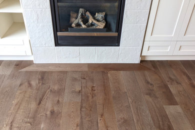 Example of a trendy medium tone wood floor living room design in Calgary with a standard fireplace and a tile fireplace