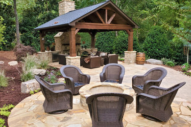 This is an example of a large country backyard patio in Atlanta with a fire feature and natural stone pavers.