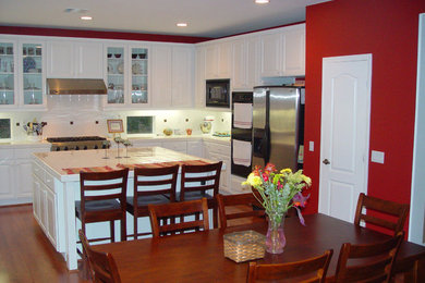 Mid-sized elegant u-shaped medium tone wood floor eat-in kitchen photo in Los Angeles with beaded inset cabinets, white cabinets, tile countertops, white backsplash, ceramic backsplash, stainless steel appliances and an island