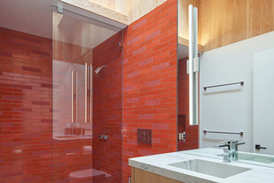 Mid-sized trendy 3/4 red tile and ceramic tile limestone floor, gray floor, single-sink, vaulted ceiling and wood wall bathroom photo in San Francisco with flat-panel cabinets, light wood cabinets, a wall-mount toilet, white walls, an integrated sink, marble countertops, gray countertops and a floating vanity
