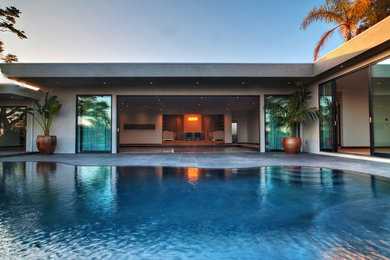 Expansive contemporary backyard custom-shaped pool in Los Angeles with concrete slab.