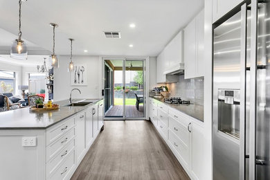 This is an example of a large traditional galley eat-in kitchen in Adelaide with a double-bowl sink, shaker cabinets, grey cabinets, quartz benchtops, grey splashback, ceramic splashback, stainless steel appliances, vinyl floors, with island, grey floor and grey benchtop.