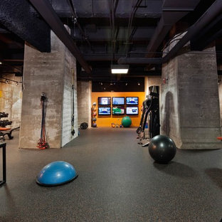 ボルチモアの大きいインダストリアルスタイルのおしゃれな多目的ジム (オレンジの壁、コルクフローリング、黒い床) の写真