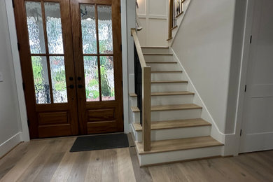 Inspiration for a medium sized modern front door in Raleigh with grey walls, light hardwood flooring, a stable front door, a dark wood front door, multi-coloured floors, a vaulted ceiling and wainscoting.