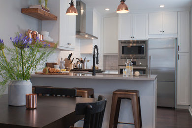 Example of a small transitional u-shaped dark wood floor eat-in kitchen design in Philadelphia with an undermount sink, recessed-panel cabinets, white cabinets, quartz countertops, white backsplash, ceramic backsplash and stainless steel appliances
