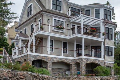 Large transitional beige three-story wood exterior home photo with a mixed material roof