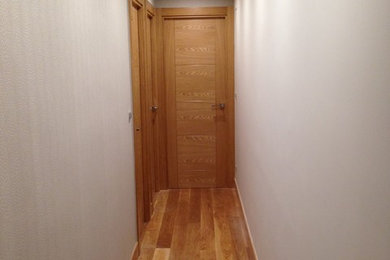 Photo of a small transitional hallway in Bilbao with white walls and medium hardwood floors.