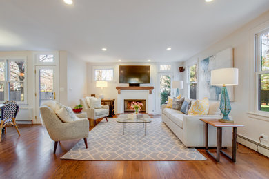 Photo of a mid-sized transitional open concept family room in Chicago with beige walls, medium hardwood floors, a standard fireplace, a brick fireplace surround, a wall-mounted tv and brown floor.