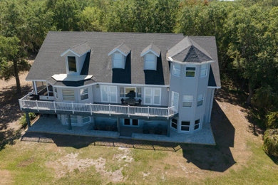 Example of a huge gray three-story vinyl and board and batten house exterior design in Miami with a clipped gable roof, a shingle roof and a gray roof