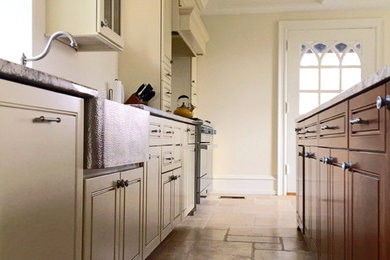 Mid-sized tuscan galley travertine floor eat-in kitchen photo in Philadelphia with a farmhouse sink, raised-panel cabinets, medium tone wood cabinets, granite countertops, stainless steel appliances and an island