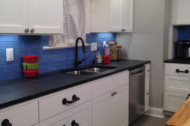 Kitchen - country painted wood floor kitchen idea in Austin with shaker cabinets, granite countertops, blue backsplash, glass tile backsplash and stainless steel appliances