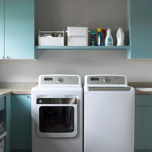 ミネアポリスのトランジショナルスタイルのおしゃれな洗濯室 (フラットパネル扉のキャビネット、青いキャビネット、ドロップインシンク、左右配置の洗濯機・乾燥機、ラミネートカウンター、ベージュのキッチンカウンター) の写真