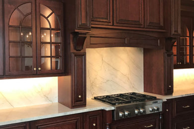 Large elegant u-shaped medium tone wood floor open concept kitchen photo in Boston with raised-panel cabinets, dark wood cabinets, marble countertops, white backsplash, marble backsplash, stainless steel appliances, an island and white countertops