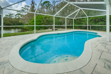 Inspiration for a mid-sized coastal backyard kidney-shaped natural pool remodel in Tampa with decking