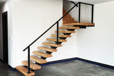Foto de escalera suspendida moderna de tamaño medio con escalones de madera y barandilla de cable