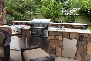 Large island style backyard stone patio kitchen photo in Phoenix with a pergola