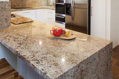 Mid-sized modern u-shaped eat-in kitchen in Perth with an undermount sink, flat-panel cabinets, white cabinets, granite benchtops, stone slab splashback, stainless steel appliances, slate floors and a peninsula.