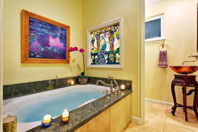 Inspiration for a large master bathroom remodel in Hawaii with a vessel sink, raised-panel cabinets, dark wood cabinets, solid surface countertops, green walls and an undermount tub