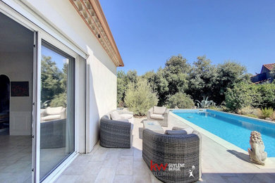 Imagen de piscina mediterránea grande rectangular en patio trasero con suelo de baldosas