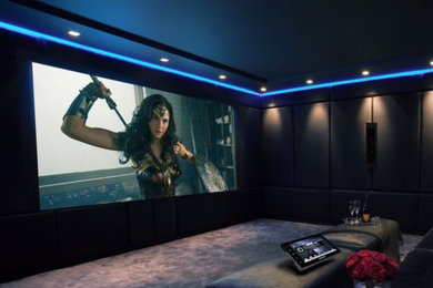 Ejemplo de cine en casa cerrado contemporáneo de tamaño medio con paredes azules, moqueta, pantalla de proyección y suelo multicolor