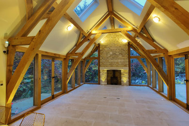 Photo of a medium sized contemporary living room in Gloucestershire with beige walls, limestone flooring, a wood burning stove, a stone fireplace surround, beige floors and a vaulted ceiling.