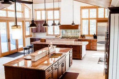 Eat-in kitchen - huge rustic eat-in kitchen idea in Grand Rapids with flat-panel cabinets, medium tone wood cabinets, granite countertops, green backsplash, ceramic backsplash, stainless steel appliances and two islands