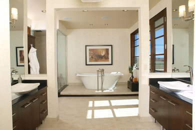Large trendy master porcelain tile and beige floor freestanding bathtub photo in Denver with flat-panel cabinets, dark wood cabinets, beige walls, a vessel sink and quartz countertops