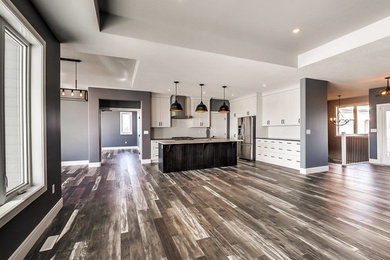 Example of a mid-sized arts and crafts l-shaped laminate floor and gray floor eat-in kitchen design in Edmonton with a double-bowl sink, recessed-panel cabinets, white cabinets, quartzite countertops, white backsplash, porcelain backsplash, stainless steel appliances and an island
