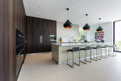 Inspiration for a large contemporary l-shaped eat-in kitchen in Los Angeles with a single-bowl sink, flat-panel cabinets, dark wood cabinets, quartz benchtops, white splashback, glass sheet splashback, black appliances, ceramic floors, with island and beige floor.