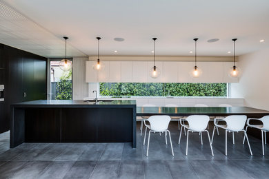 Photo of a contemporary galley eat-in kitchen in Sydney with an undermount sink, flat-panel cabinets, wood benchtops, with island, glass sheet splashback, stainless steel appliances, ceramic floors and black floor.