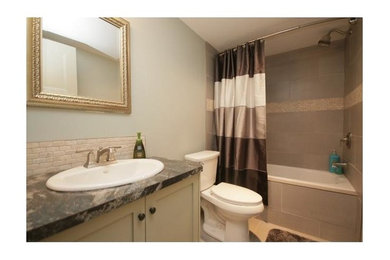 Bathroom - transitional white tile and stone tile porcelain tile bathroom idea in Calgary with shaker cabinets, white cabinets, a two-piece toilet, green walls, a drop-in sink and laminate countertops