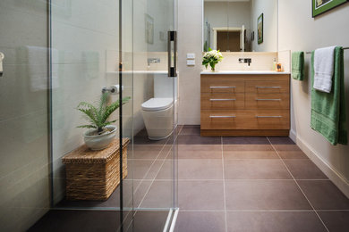 Photo of a mid-sized modern bathroom in Melbourne with medium wood cabinets, a double shower, a two-piece toilet, brown tile, porcelain tile, beige walls, porcelain floors, an integrated sink and solid surface benchtops.