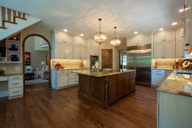 Ejemplo de cocina comedor clásica con encimera de granito, electrodomésticos de acero inoxidable, suelo de madera en tonos medios y una isla