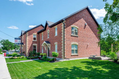 Large traditional two-story brick exterior home idea in Toronto with a metal roof