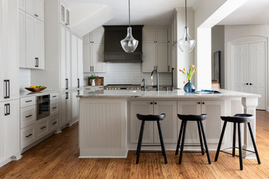 Idéer för ett stort klassiskt grå kök, med en rustik diskho, luckor med upphöjd panel, grå skåp, bänkskiva i kvartsit, vitt stänkskydd, stänkskydd i keramik, integrerade vitvaror, mellanmörkt trägolv, en halv köksö och brunt golv