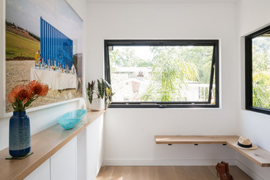 Entryway - small contemporary light wood floor and beige floor entryway idea in San Francisco with white walls and a black front door