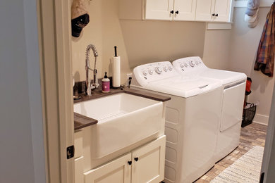 Example of a large farmhouse single-wall ceramic tile and multicolored floor utility room design in Nashville with a farmhouse sink, shaker cabinets, white cabinets, granite countertops, beige walls, a side-by-side washer/dryer and gray countertops