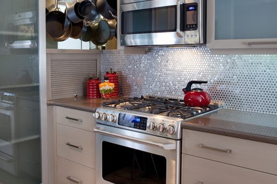 Small minimalist u-shaped vinyl floor kitchen photo in San Diego with glass-front cabinets, gray cabinets, quartzite countertops, metallic backsplash, metal backsplash, stainless steel appliances and no island