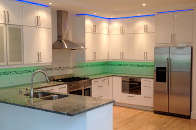 Kitchen - modern u-shaped light wood floor kitchen idea in Atlanta with a double-bowl sink, white backsplash, mosaic tile backsplash, stainless steel appliances, flat-panel cabinets, white cabinets, granite countertops and a peninsula