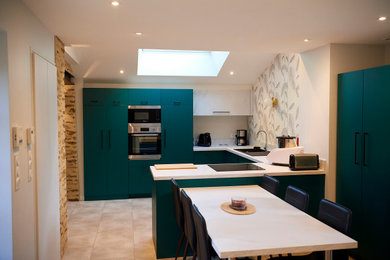 This is an example of a large country u-shaped open plan kitchen in Angers with a single-bowl sink, flat-panel cabinets, green cabinets, laminate benchtops, white splashback, stainless steel appliances, vinyl floors, grey floor and white benchtop.