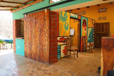 お手頃価格の中くらいなトロピカルスタイルのおしゃれな玄関 (木目調のドア、マルチカラーの壁、トラバーチンの床) の写真