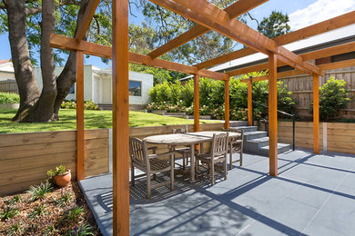 This is an example of a mid-sized modern backyard patio in Melbourne with natural stone pavers.